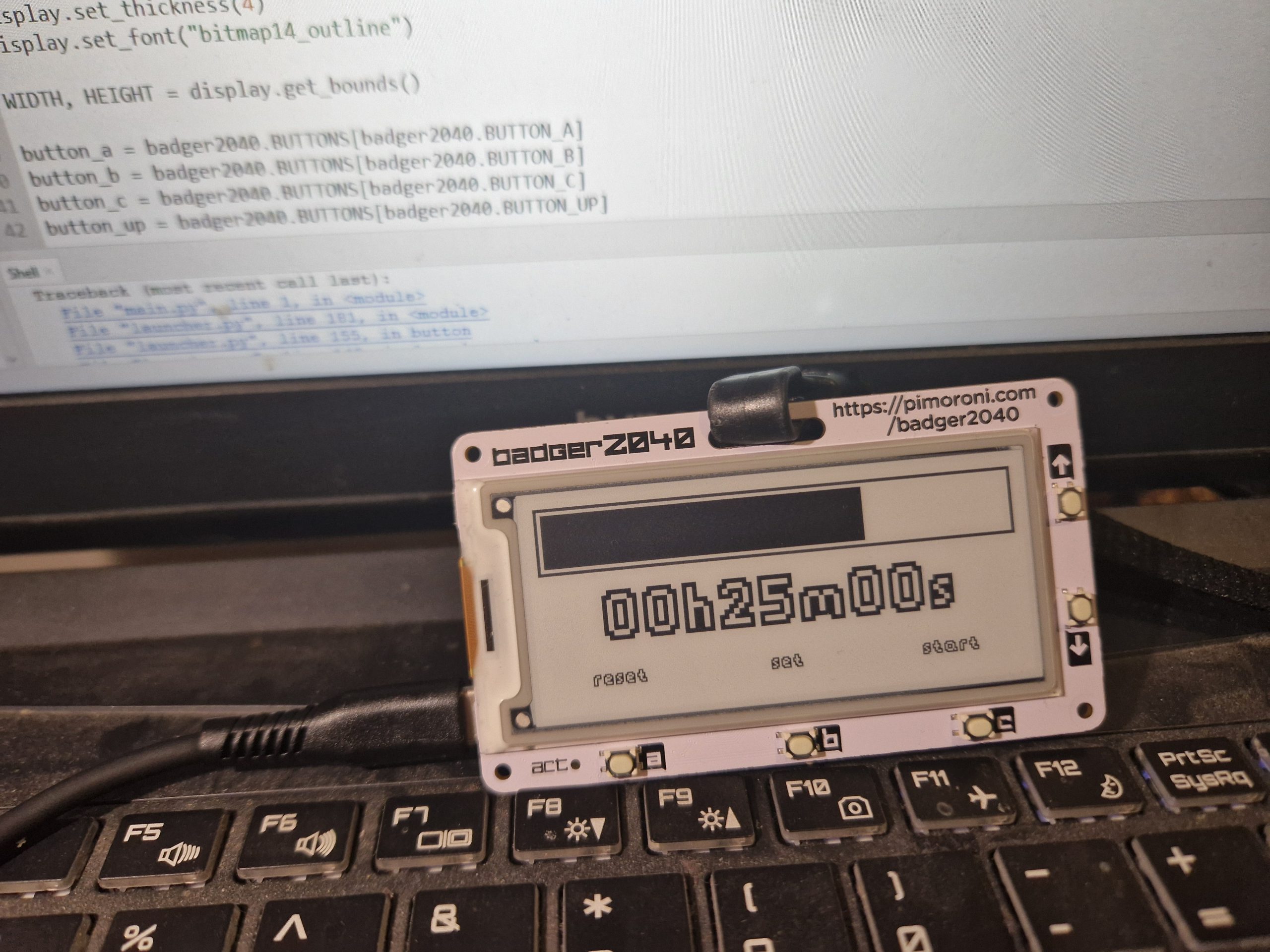 Badger2040 - z aplikacją pomodoro timera w postaci paska postęp. W tle kawałek koduz Thonny IDE